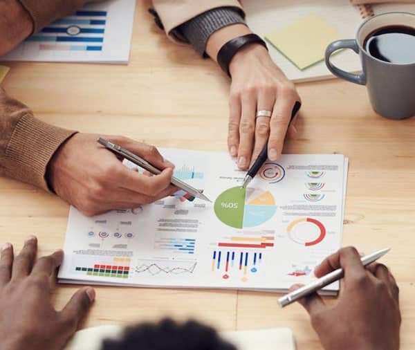 People-sat-round-desk-looking-at-graphs-on-paper