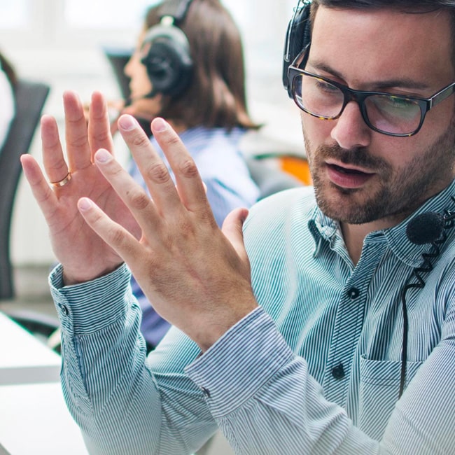 Man at a desk wearing headphones, having a conversation in a call centre
