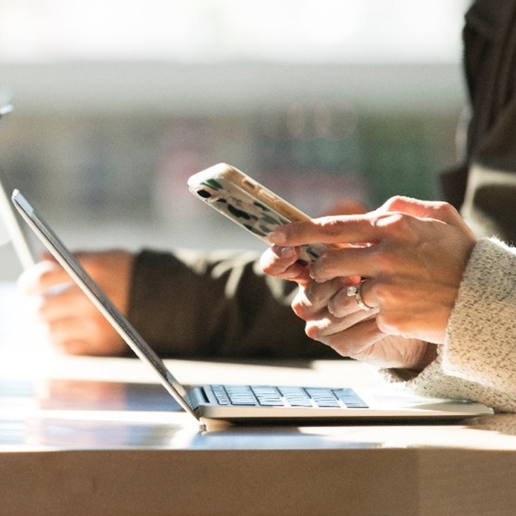 Person at desk with mobile phone in hand.